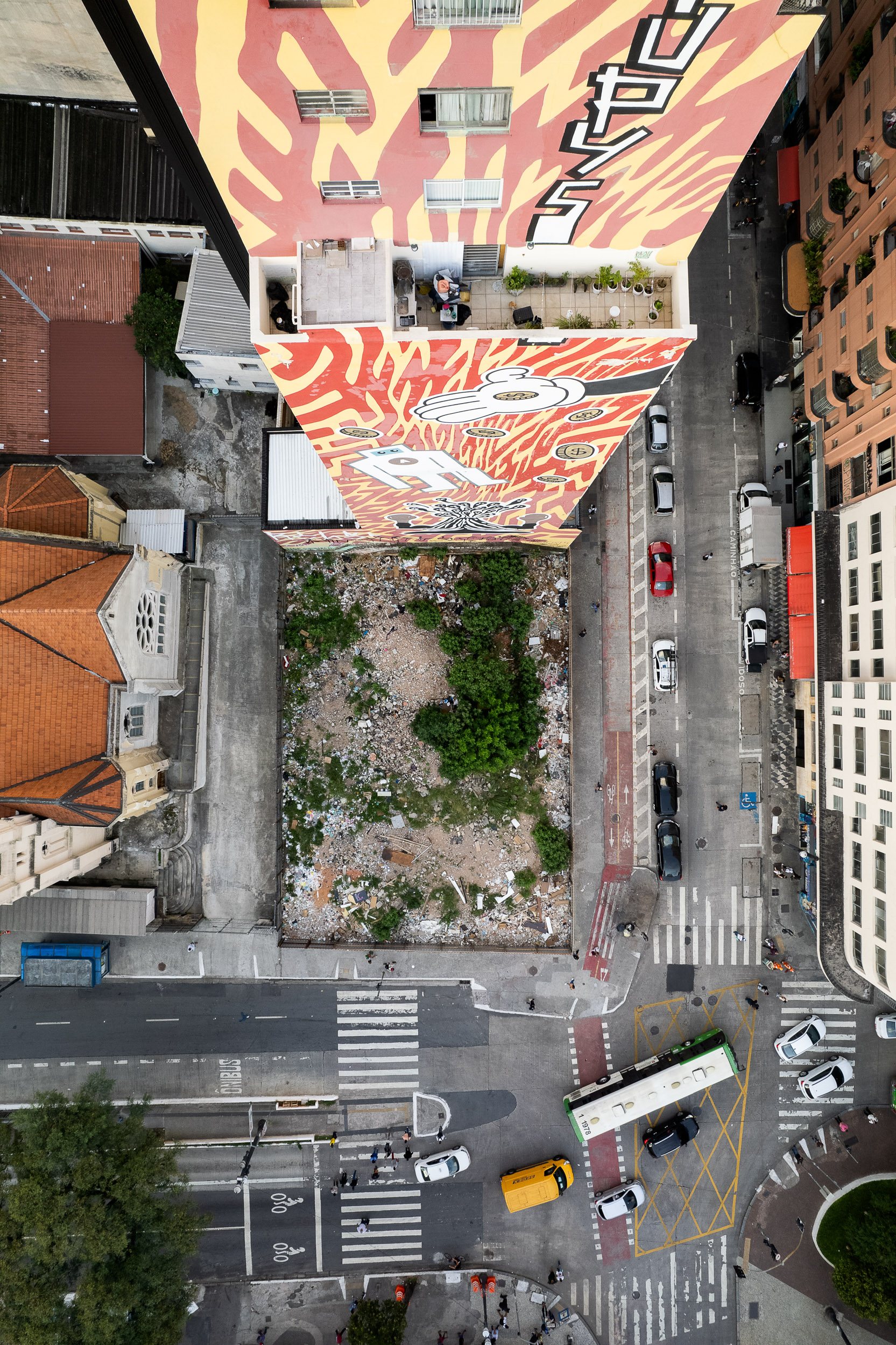 a fire-damaged vacant lot surrounded by colorful graffiti-covered buildings in São Paulo.