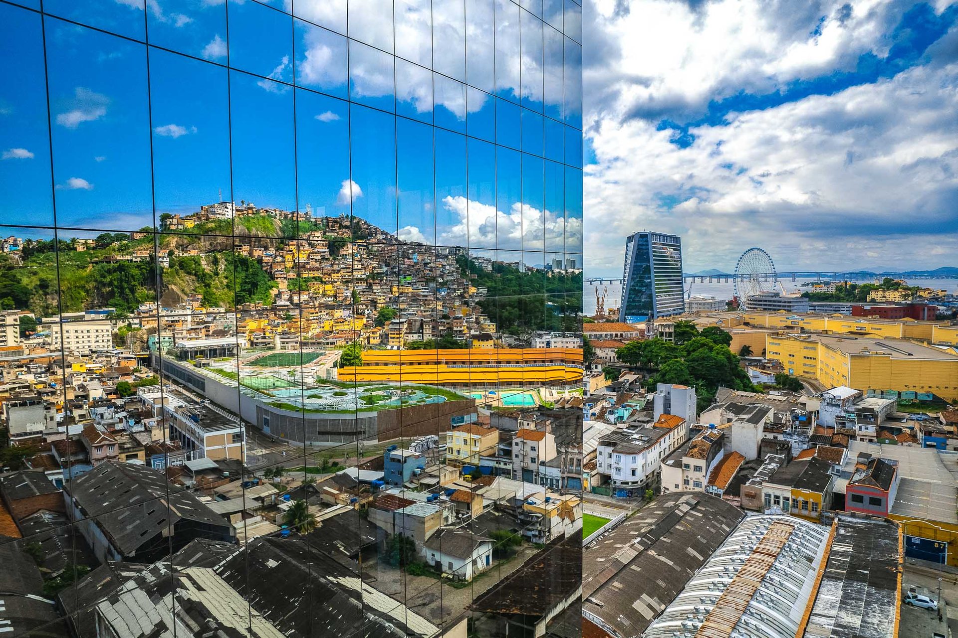 Reflection of Rio’s Morro da Providência favela in the glass windows of a modern office tower, juxtaposing historical and contemporary urban landscapes.