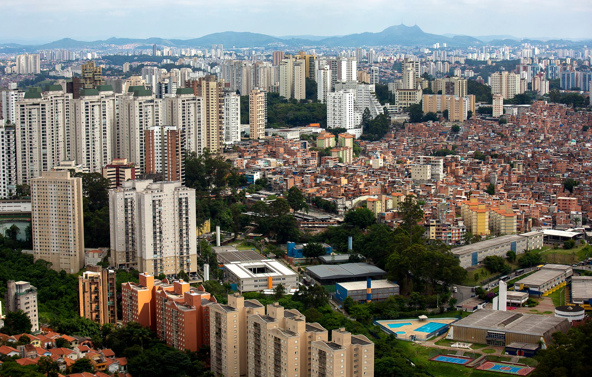 Aerial view of São Paulo showing high-rise residential buildings interspersed with a large favela.