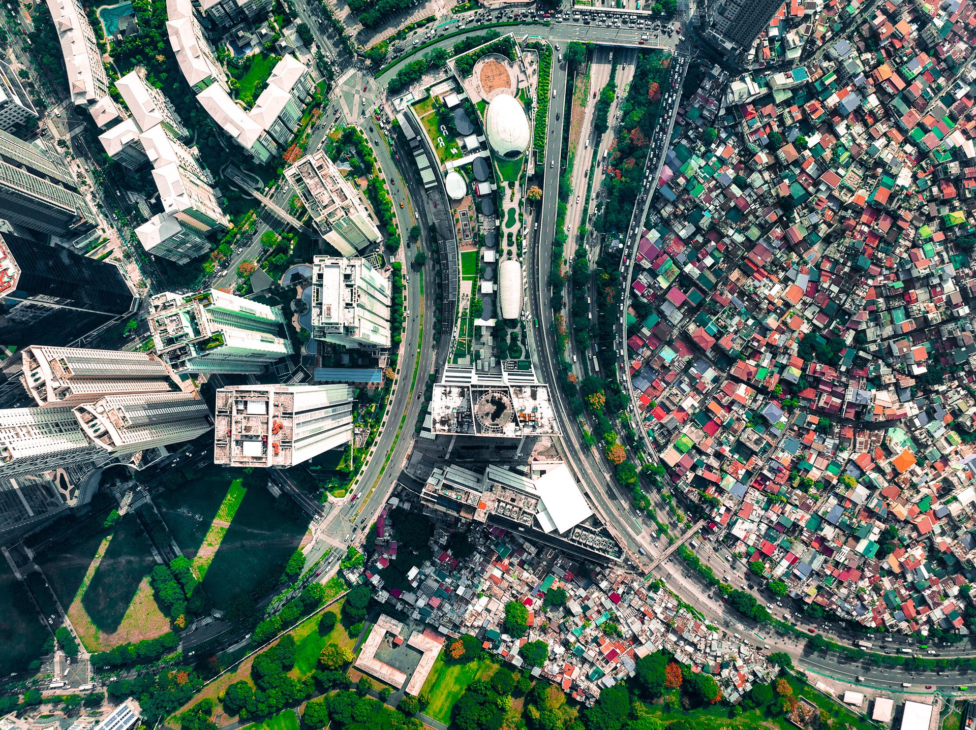 Drone image of Bonifacio Global City (BGC) and Makati in Metro Manila, where luxury skyscrapers and planned urban infrastructure sharply contrast with densely packed informal housing.