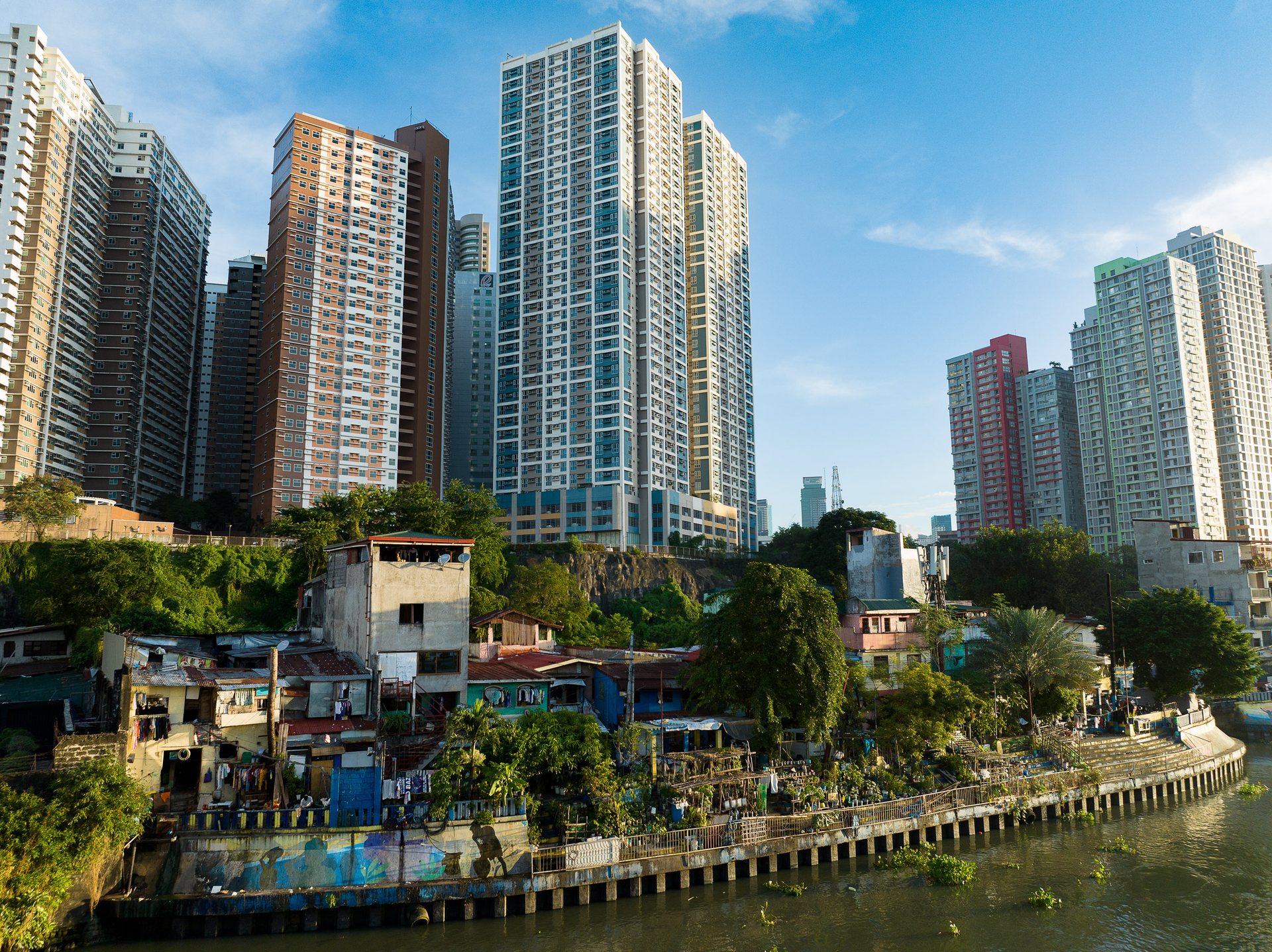 Juxtaposition of gleaming high-rise towers beside informal riverside homes.