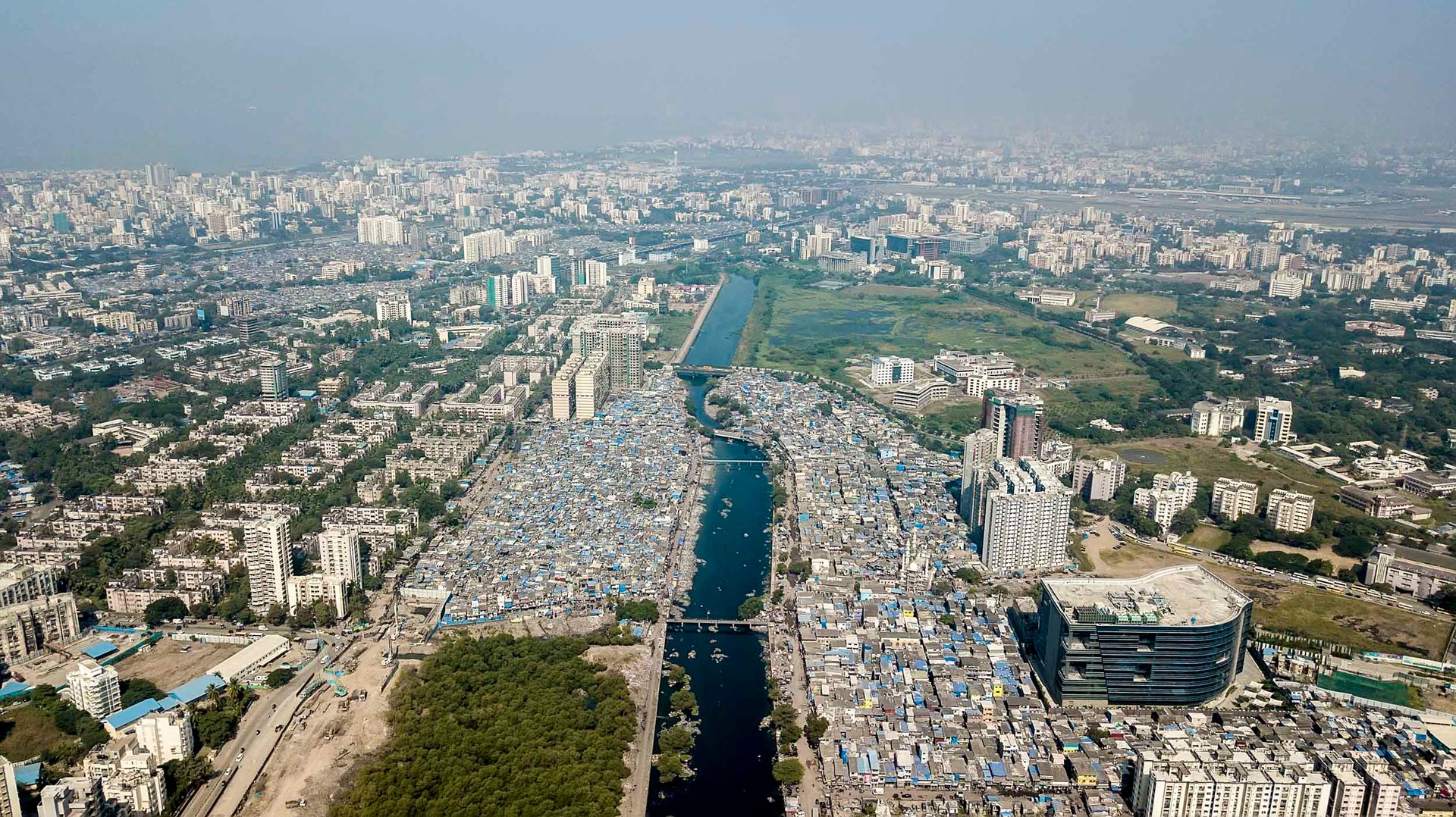 Drone image of the Mithi River flanked by informal settlements and high-rise commercial complexes.
