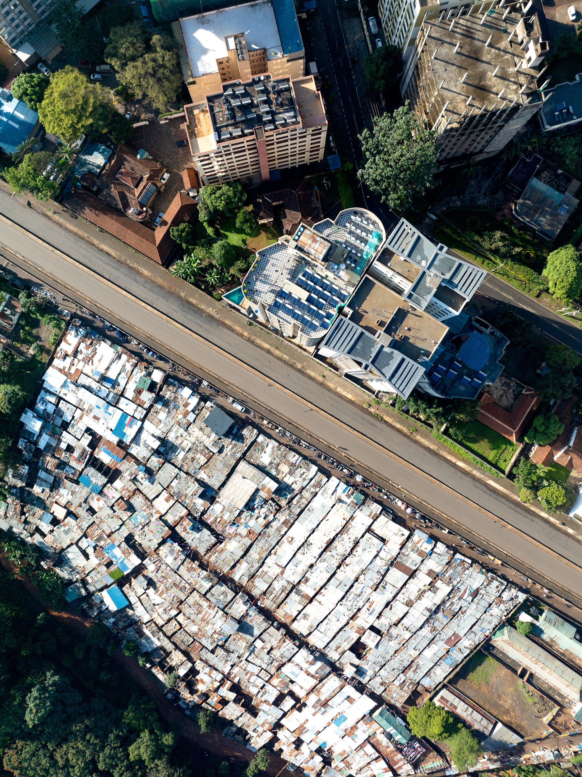 Drone image of luxury high-rise construction in Nairobi next to crowded informal housing.