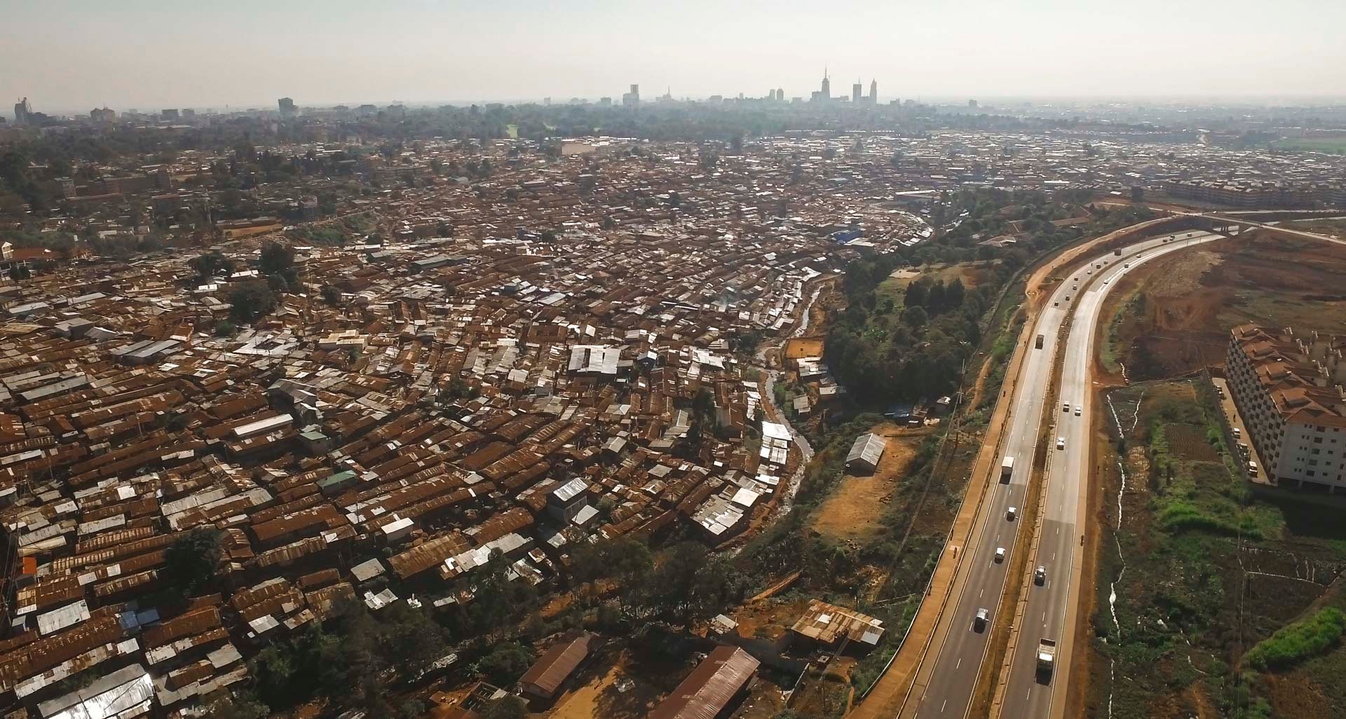 Drone photo of Nairobi expressway with informal settlement tightly built up along its edge.