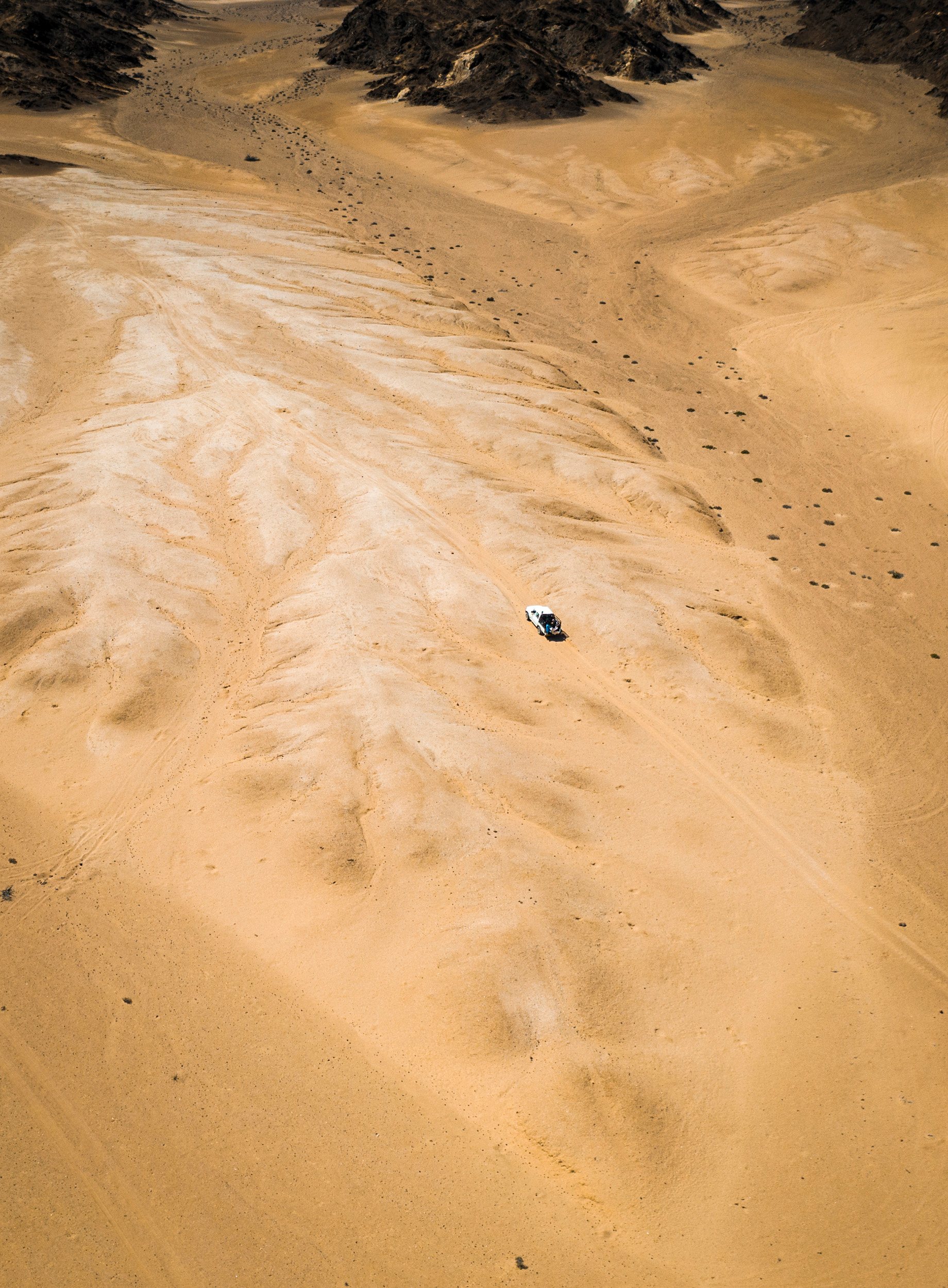 aerial view of jeep driving in sand dunes