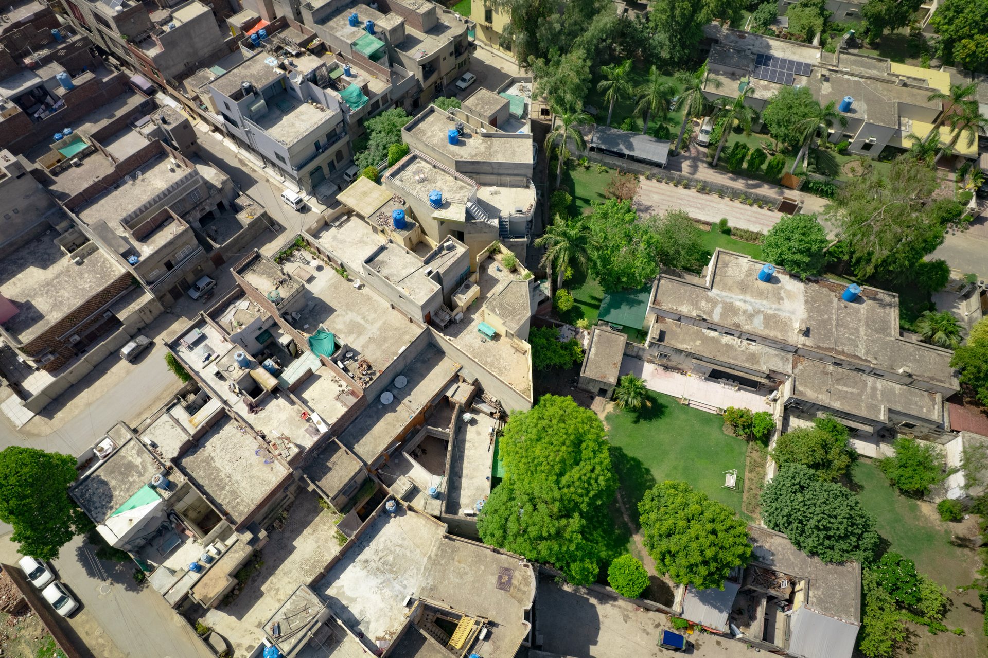 A drone view of a green neighborhood and a grey neighborhood.