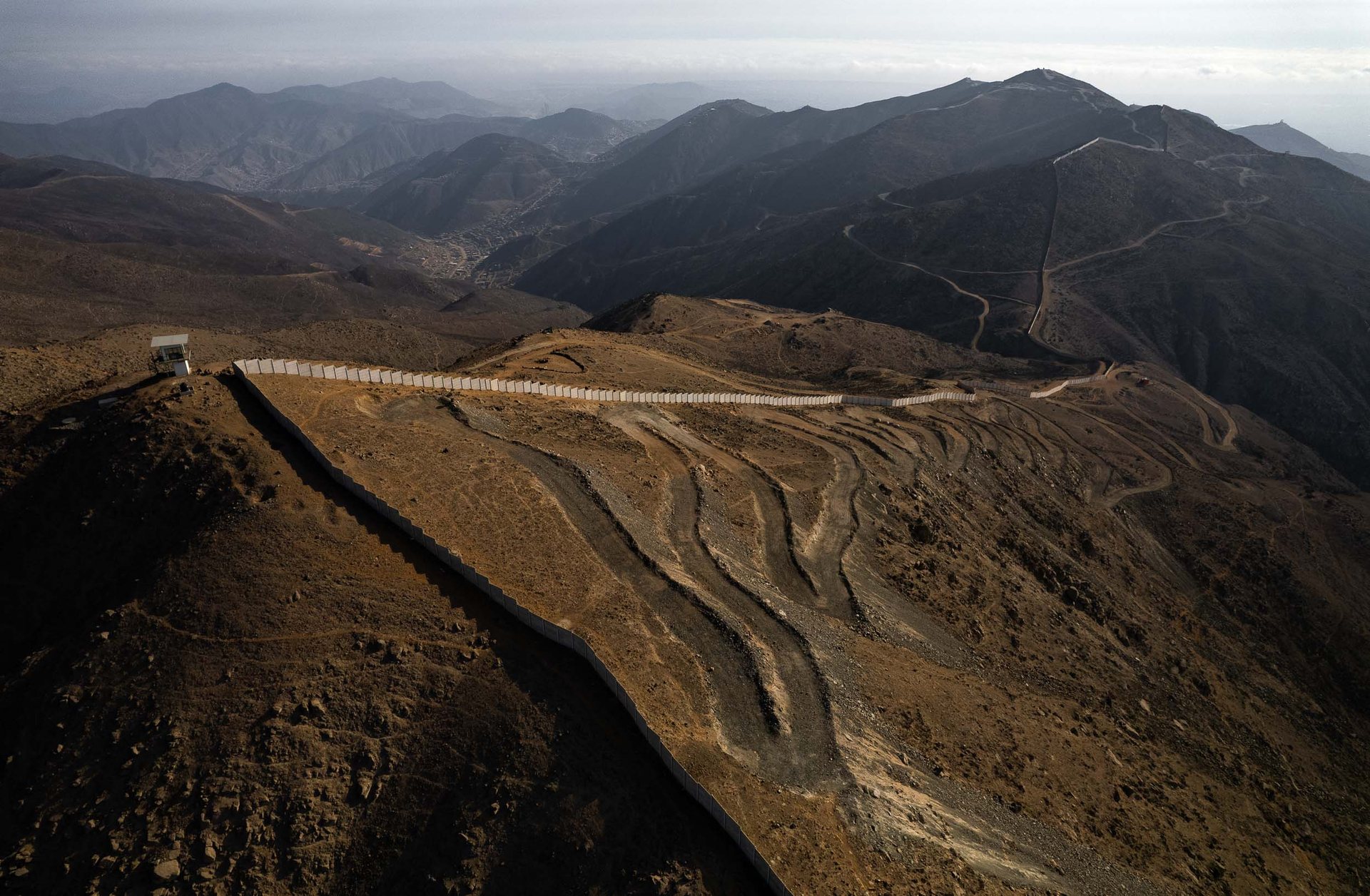 Long separation wall in Lima stretches across mountain ridge, dividing rich and poor communities.