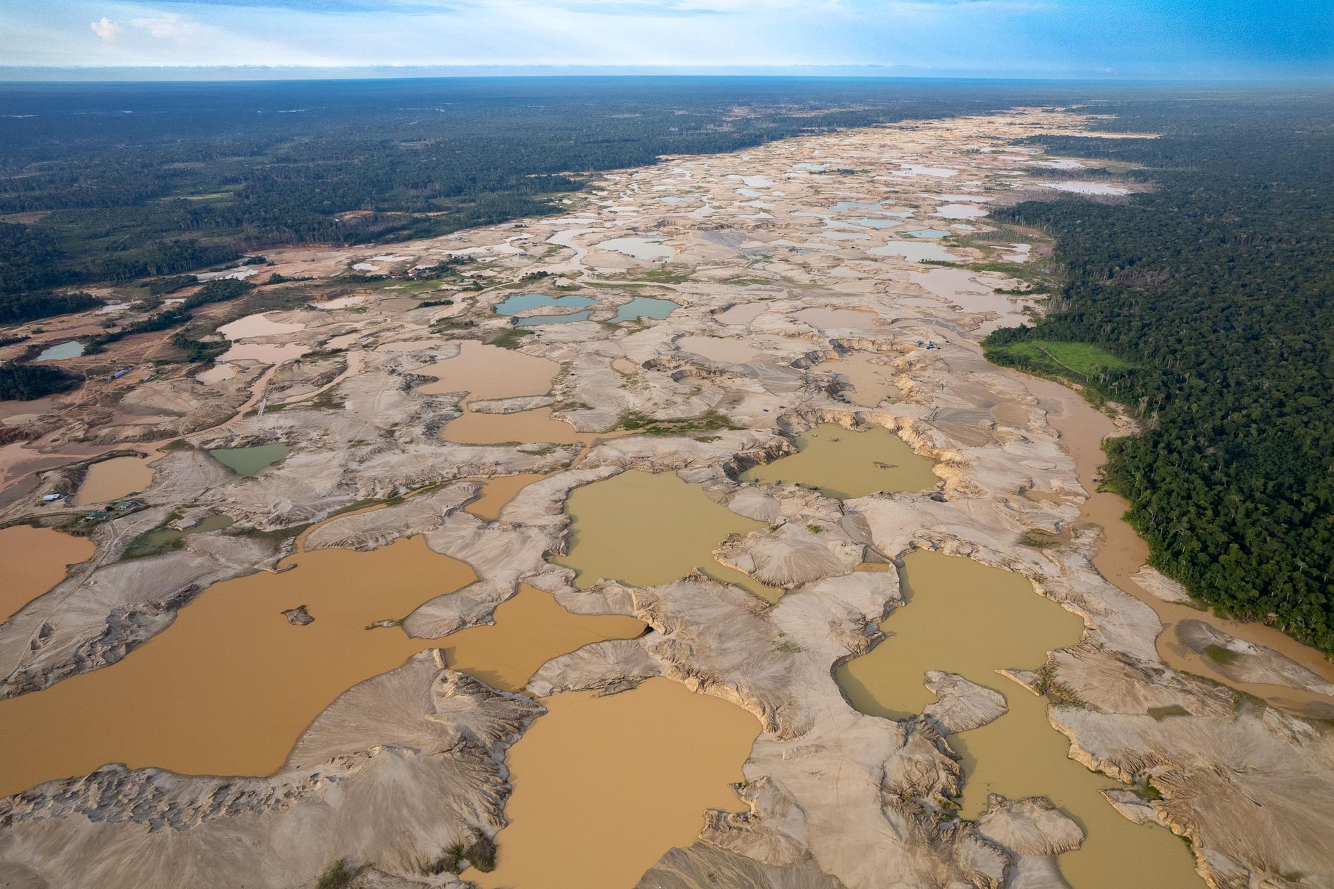 Open-pit gold mining scars the landscape of the Peruvian Amazon rainforest.