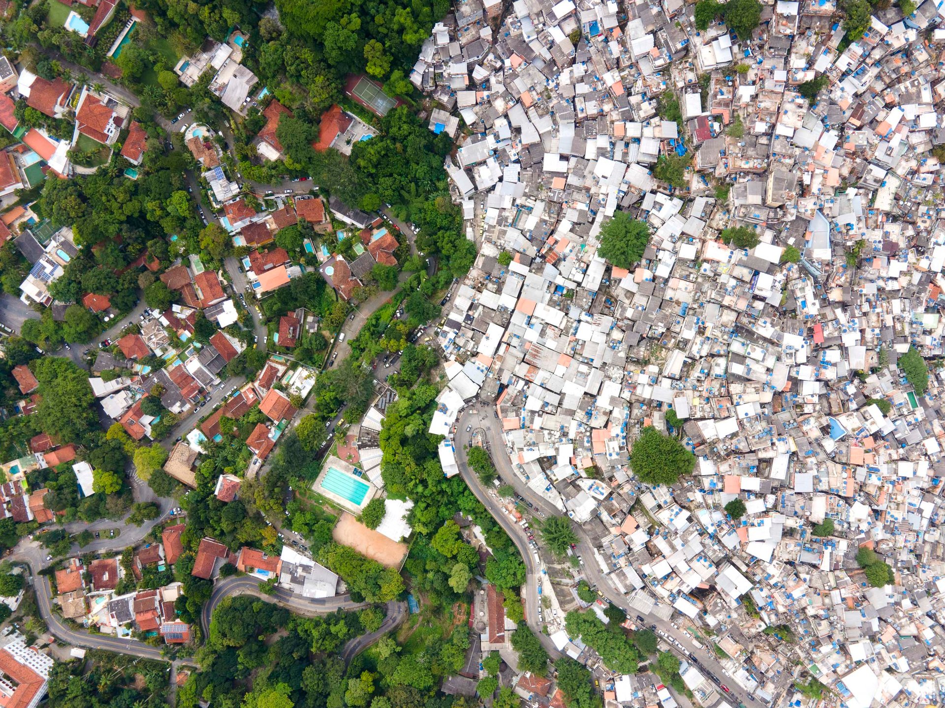 Aerial view of Rocinha favela bordered by wealthier neighborhoods in Rio de Janeiro, illustrating stark spatial inequality.