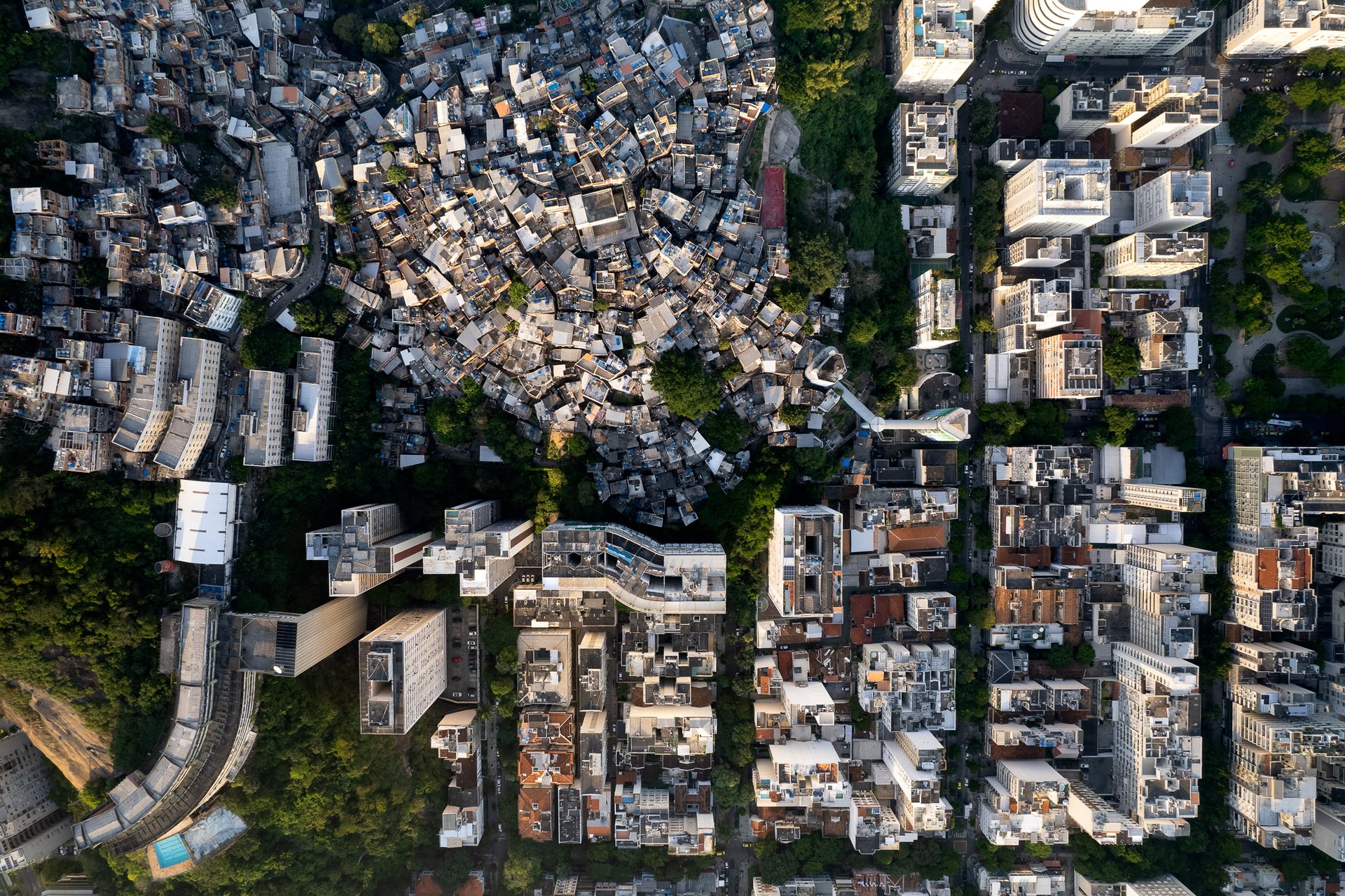 Massive concrete housing blocks rise above tightly packed blue-roofed homes in Ipanema, Rio de Janeiro.