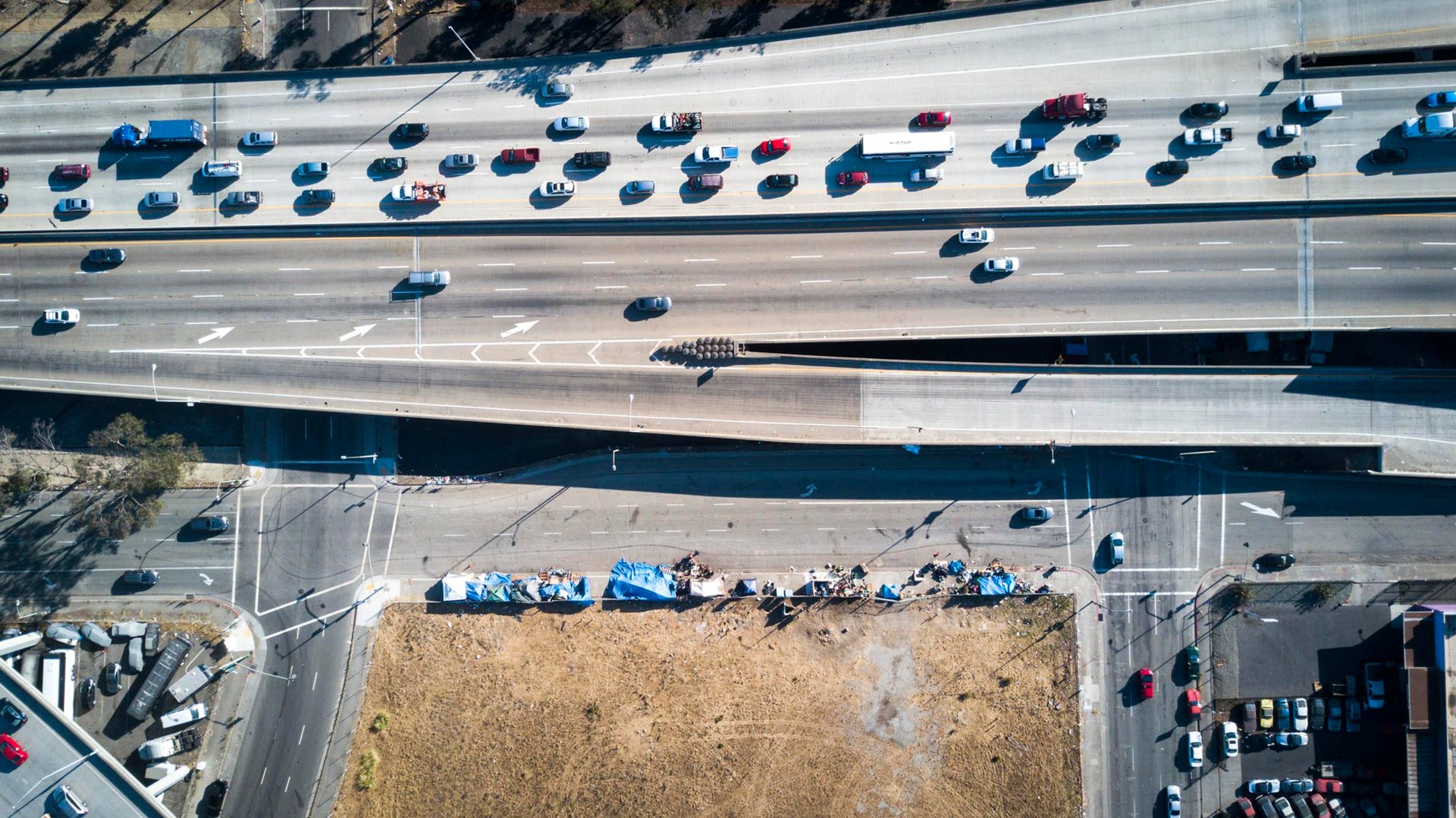 Traffic on I-880 in Oakland, CA inches past a homeless encampment during rush hour.