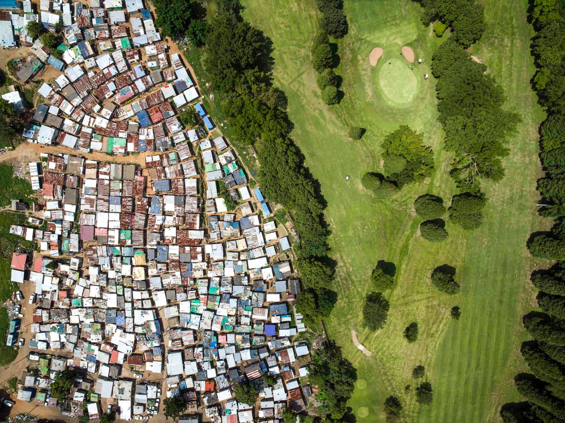 Shacks of Durban settlement directly beside Papwa Sewgolum Golf Course fairways in South Africa
