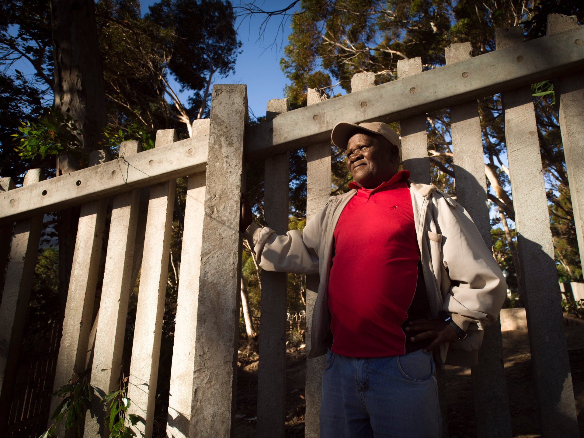Kenny Tokwe, a community leader, leans against the concrete wall which separates the community of Imizamo Yethu from Hout Bay.