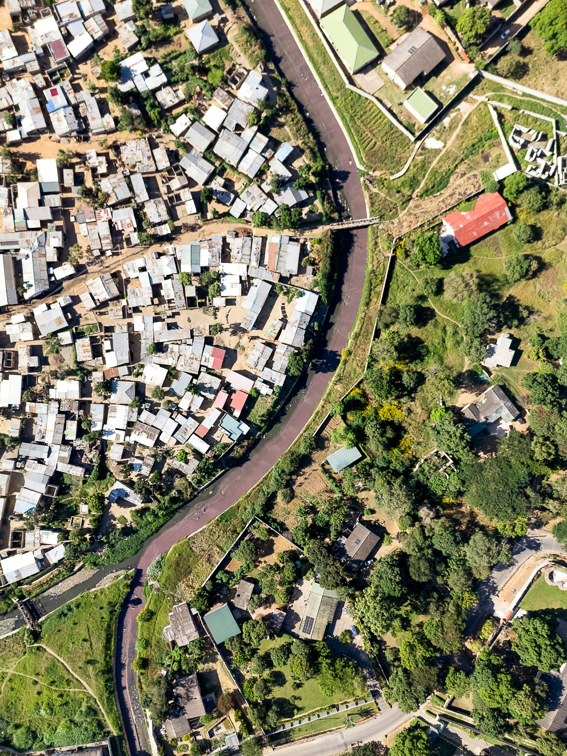 Roma and Chipata compound sit in the same northeastern slice of Lusaka — walled lots, lawns, pools, and gated complexes on one side; an informal settlement defined in the academic literature by its erratic water supply on the other.